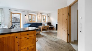 Un intérieur moderne comprenant un coin cuisine, des meubles de rangement en bois, une table à manger et un canapé bleu.