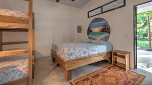 Een slaapkamer met een stapelbed, een enkel bed, een plafondventilator, een schilderij en uitzicht op de omgeving.