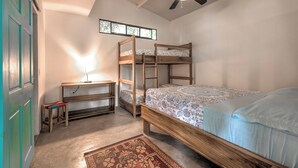 Een kamer met stapelbedden, een bureau en een plafondventilator.