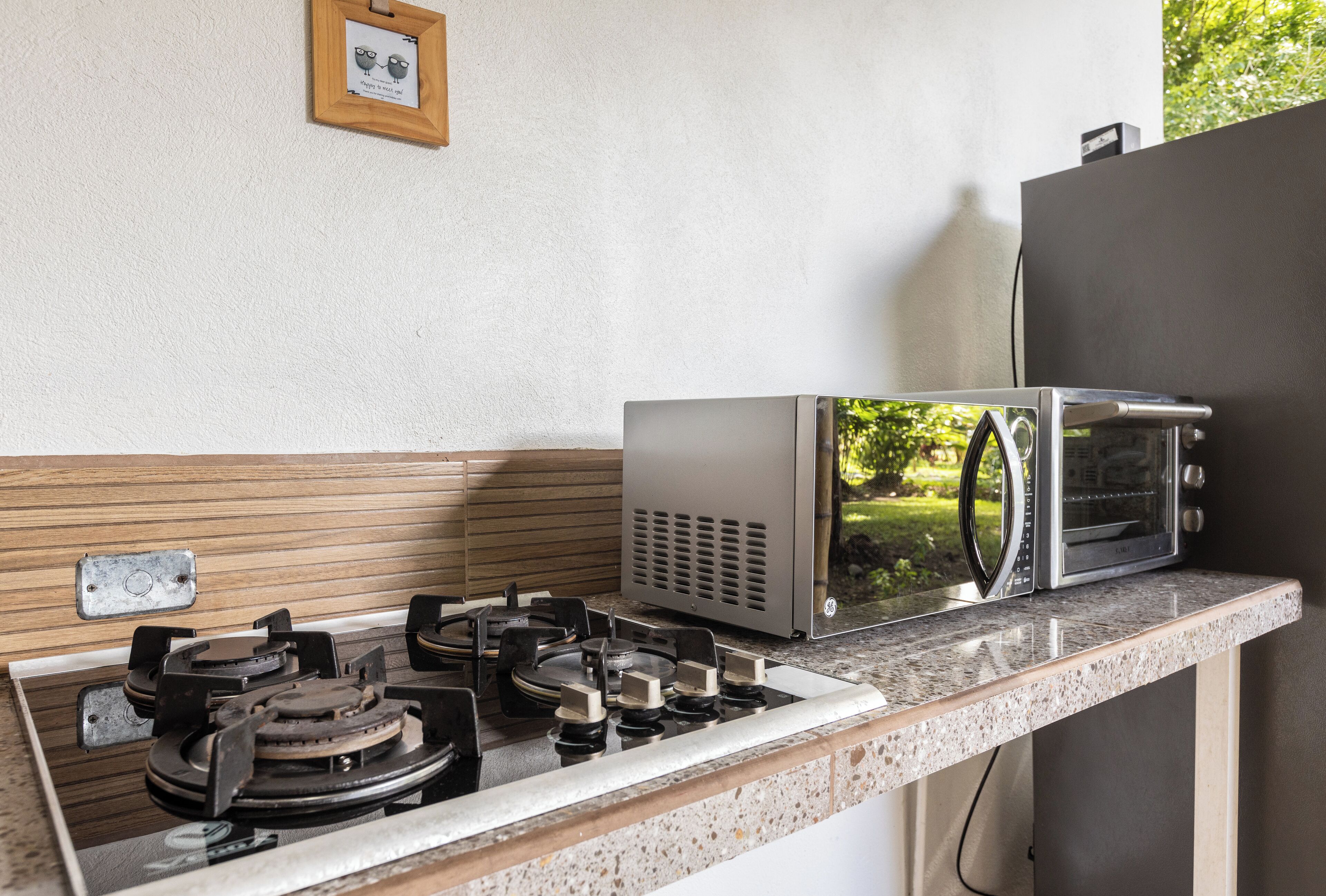 Een keuken met een gasfornuis, een magnetron en een elektrische oven op een granieten aanrecht.