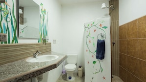 Ein Badezimmer mit einem Granitwaschbecken, einer weißen Toilette und einer Dusche mit einem Handtuch an der Wand.