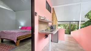 Ein Schlafzimmer mit Bett, Nachttisch und einer kleinen Küchenzeile.