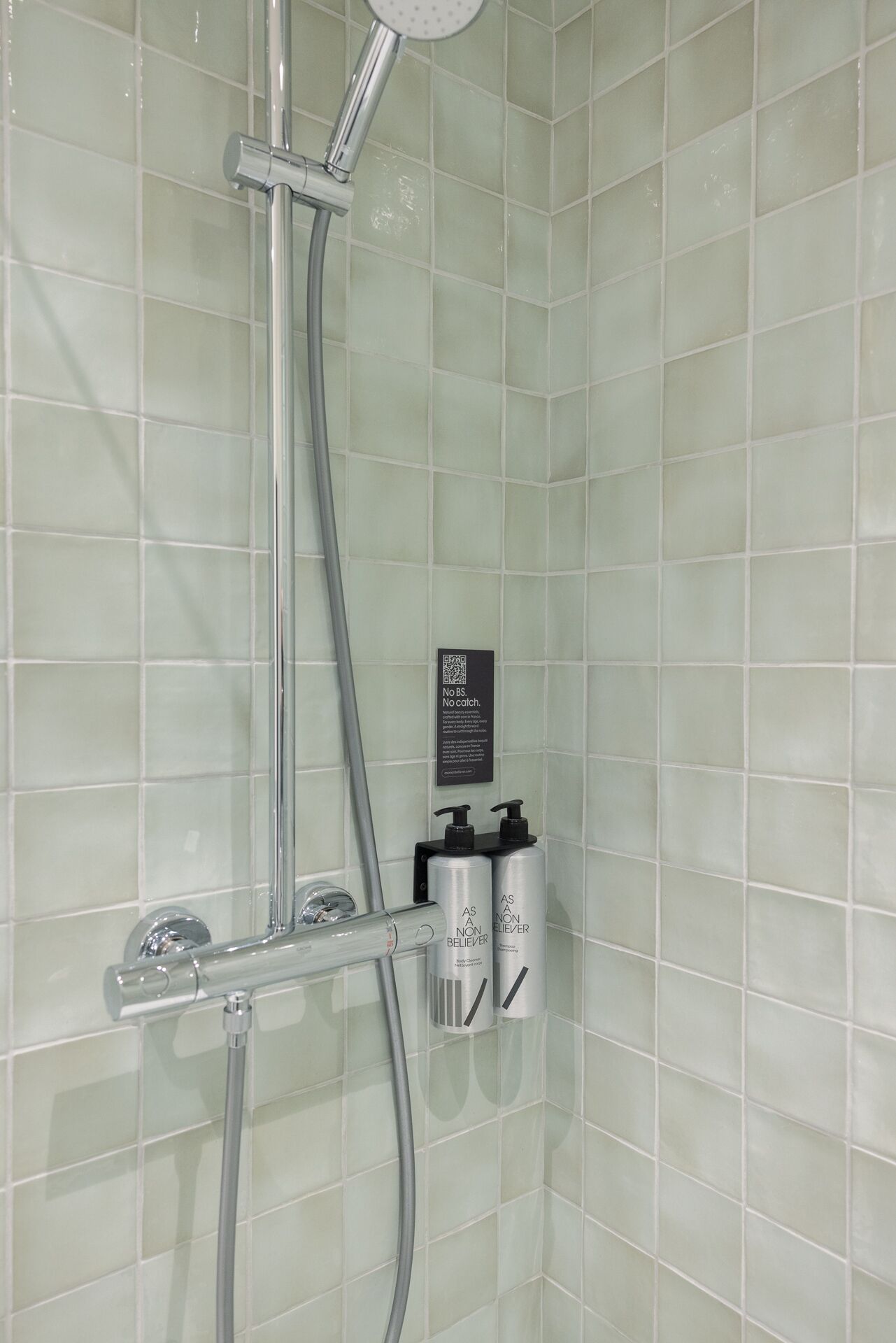 A shower with a handheld showerhead and a wall-mounted control panel.
