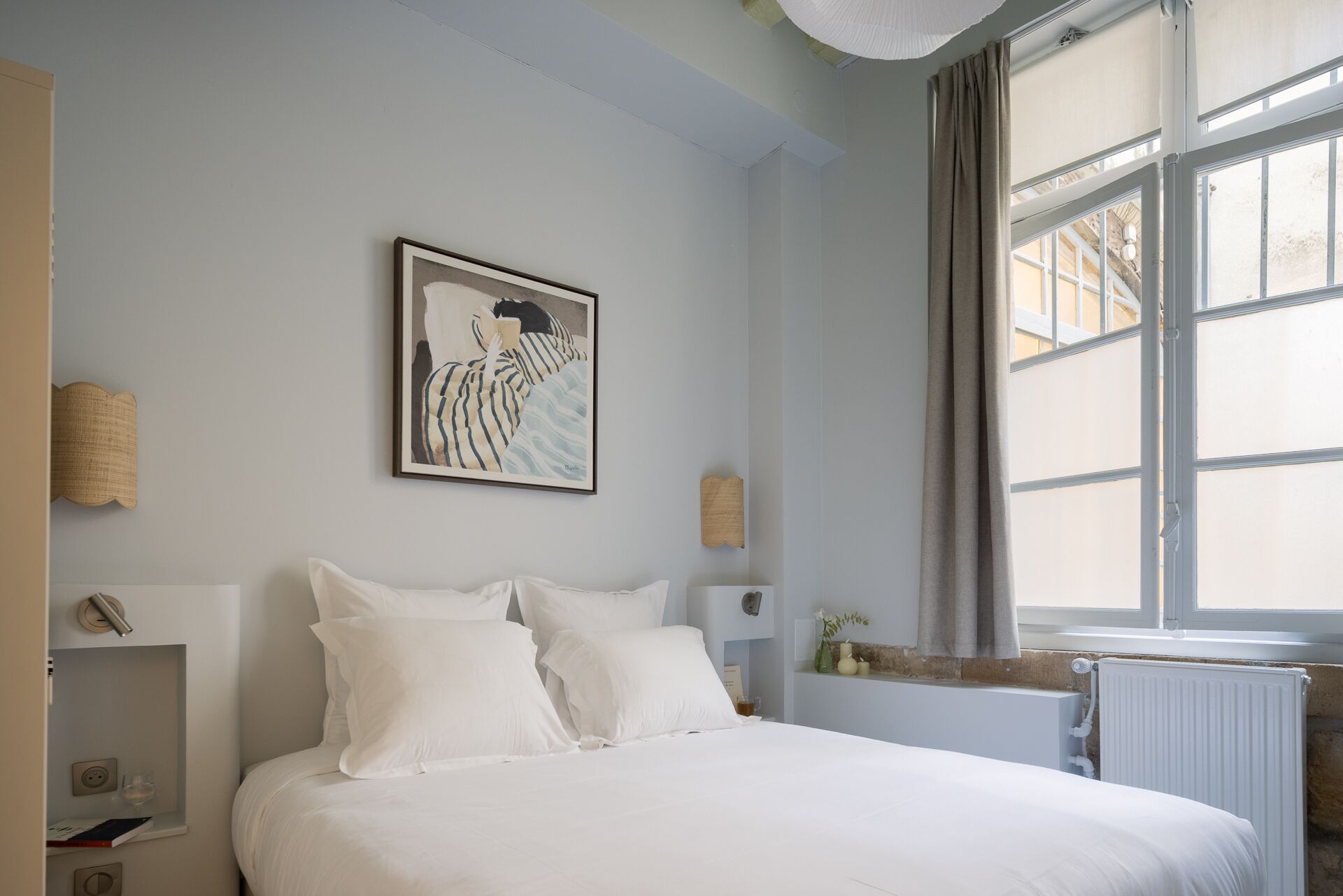 Une chambre à coucher avec un lit, un tableau, une fenêtre et un radiateur.