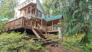 A cabin with a wooden deck, a staircase, and a view of surrounding trees. - Third night free on stays before 8/30/26 (Government Camp)