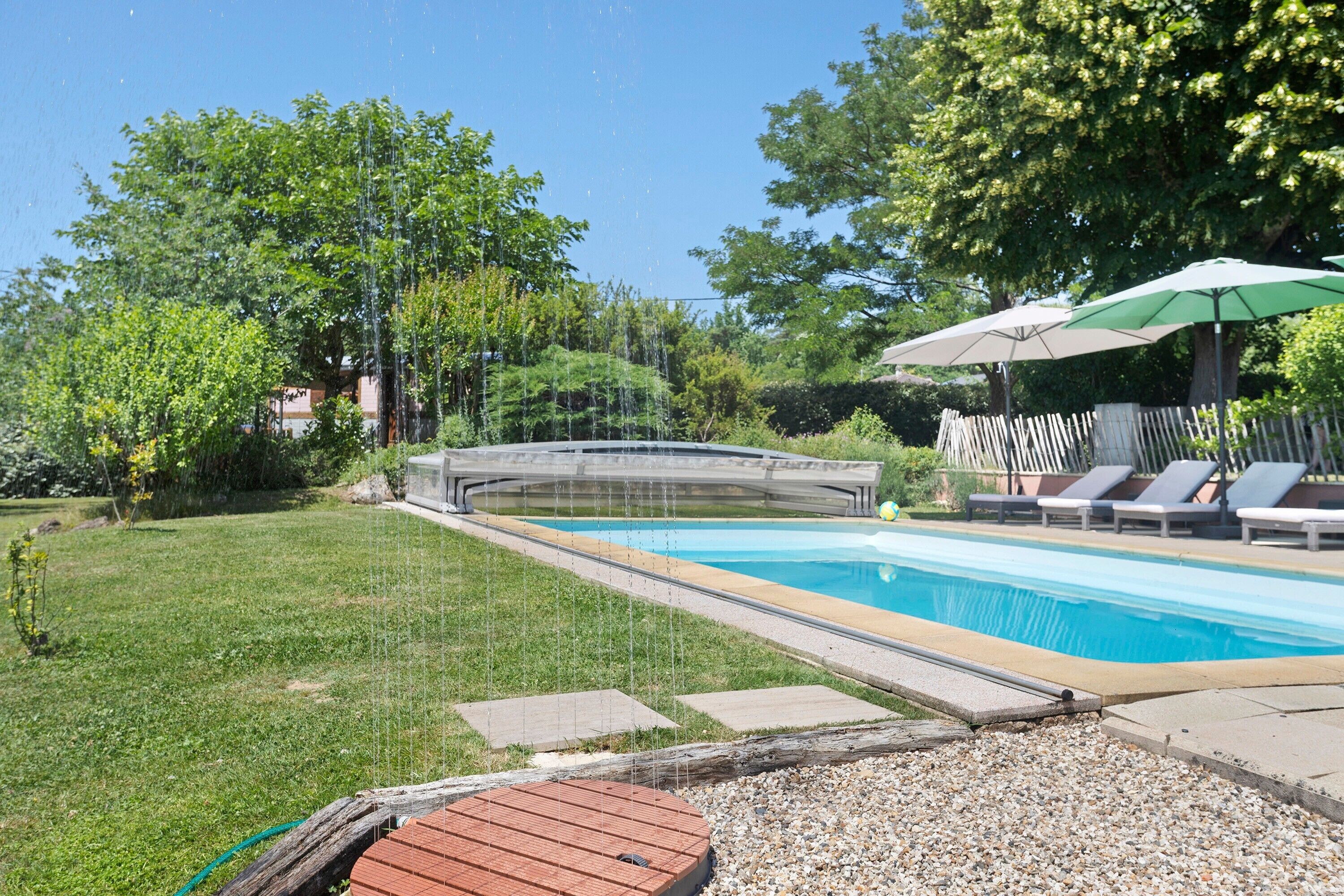 A swimming pool with a wooden deck, lounge chairs, and umbrellas.