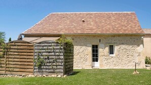 A stone building with a tiled roof, a wooden fence, and a small window.