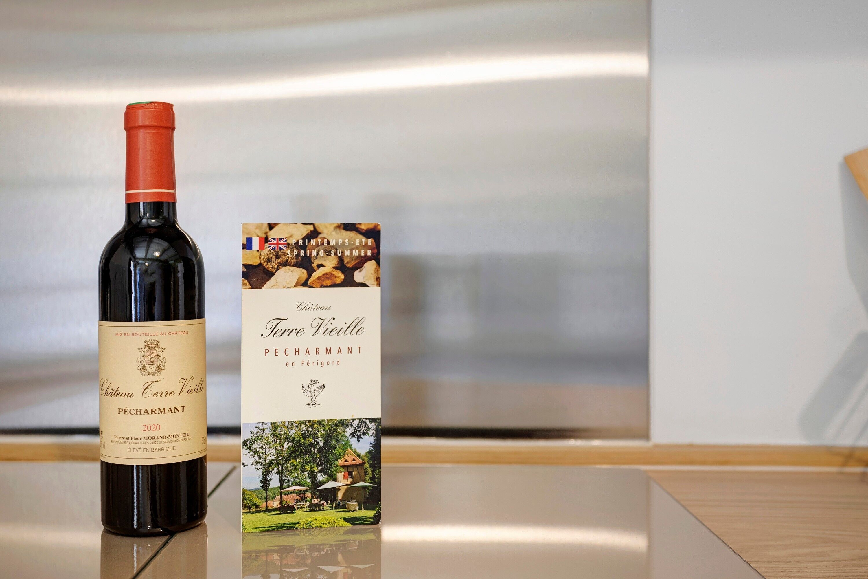 Una bottiglia di vino Chateau Ferre Vieille Pêchearmant e la sua confezione su una superficie riflettente.