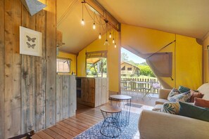 Un intérieur chaleureux avec des murs en bois, un coin repas et un canapé agrémenté de coussins à motifs.