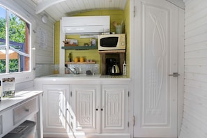 Una cocina con armarios blancos, un microondas y una ventana con vistas a árboles.