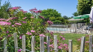 Ein Holzzaun, ein Pool und grüne Sonnenschirme in einem Garten.