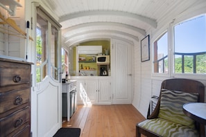 Una cocina compacta con muebles blancos, un microondas y un lavabo.