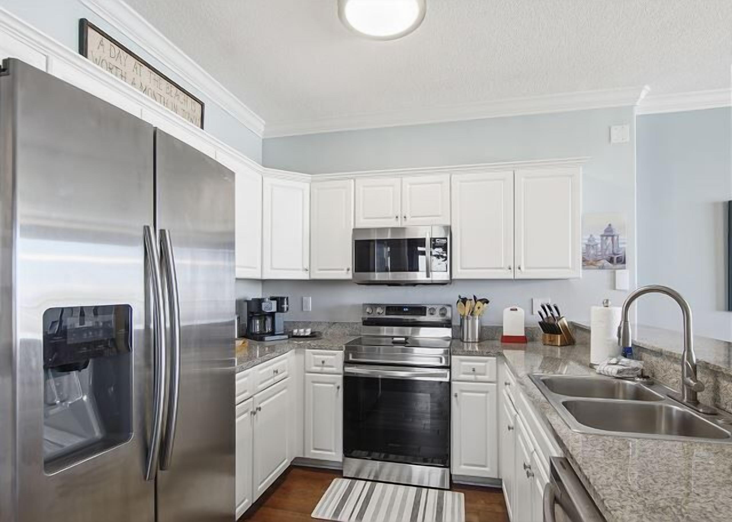 A modern kitchen with stainless steel appliances, white cabinetry, and granite countertops.