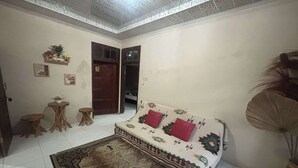 A living room with a sofa, a patterned rug, a small table, and a decorative fan.
