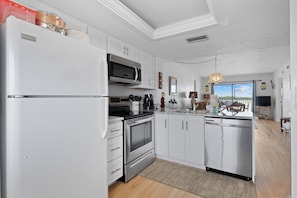 A modern kitchen with white cabinetry, stainless steel appliances, and a view to the outside.