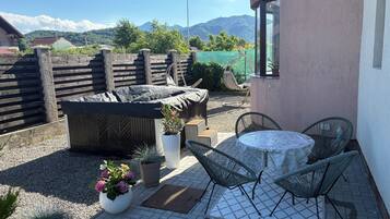 A patio with a table and chairs, a covered seating area, and a view of mountains.