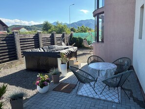 A patio with a table and chairs, a covered seating area, and a view of mountains.