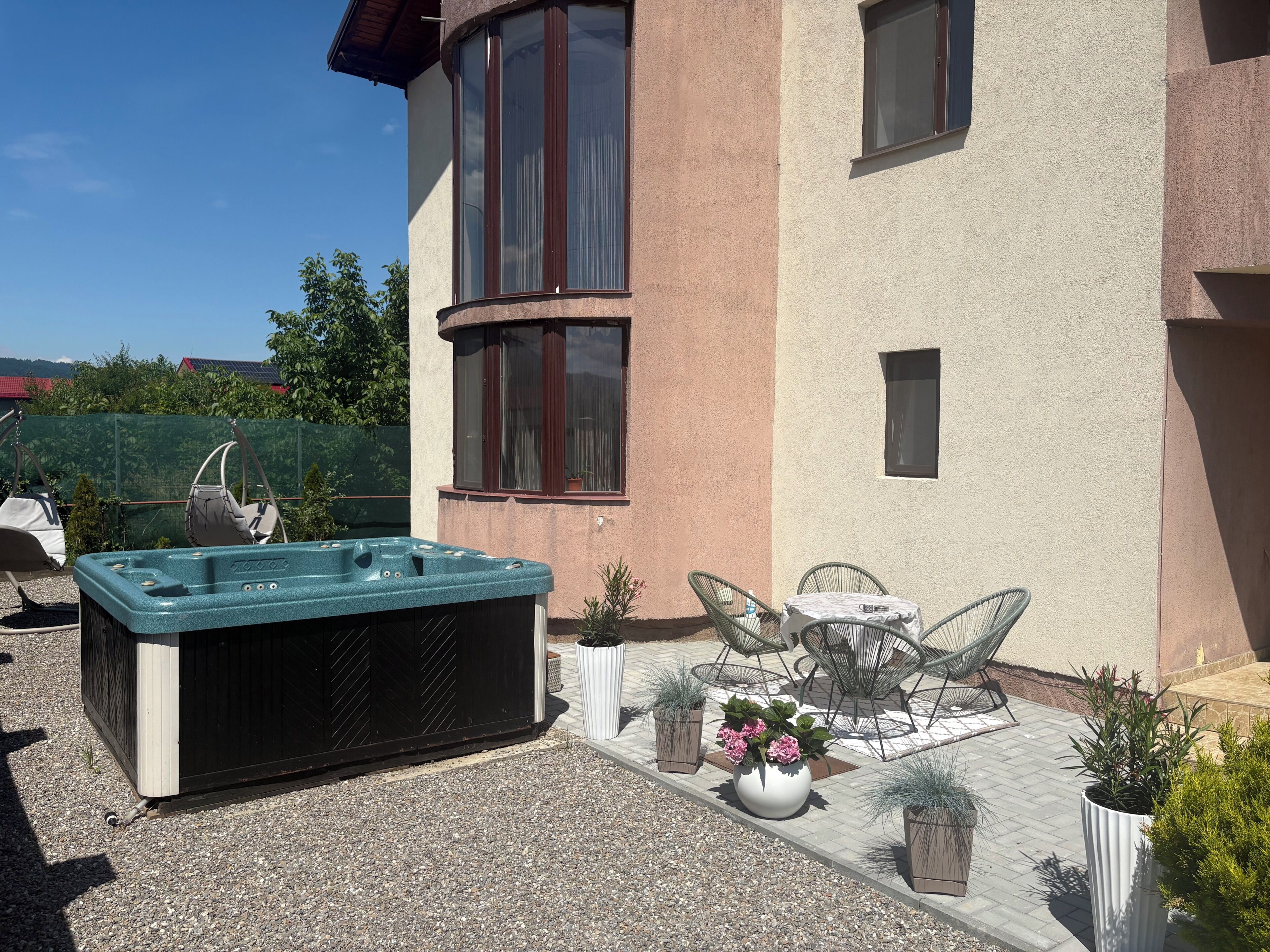 A spa area with a hot tub, outdoor seating, and potted plants.
