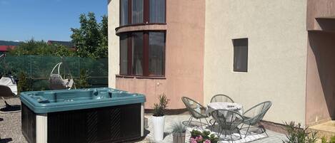 A spa area with a hot tub, outdoor seating, and potted plants.
