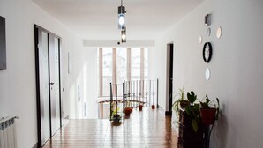 A spacious hallway with wooden flooring, a hanging light fixture, and potted plants. - Mik Chalet. Pet friendly (Săcele)