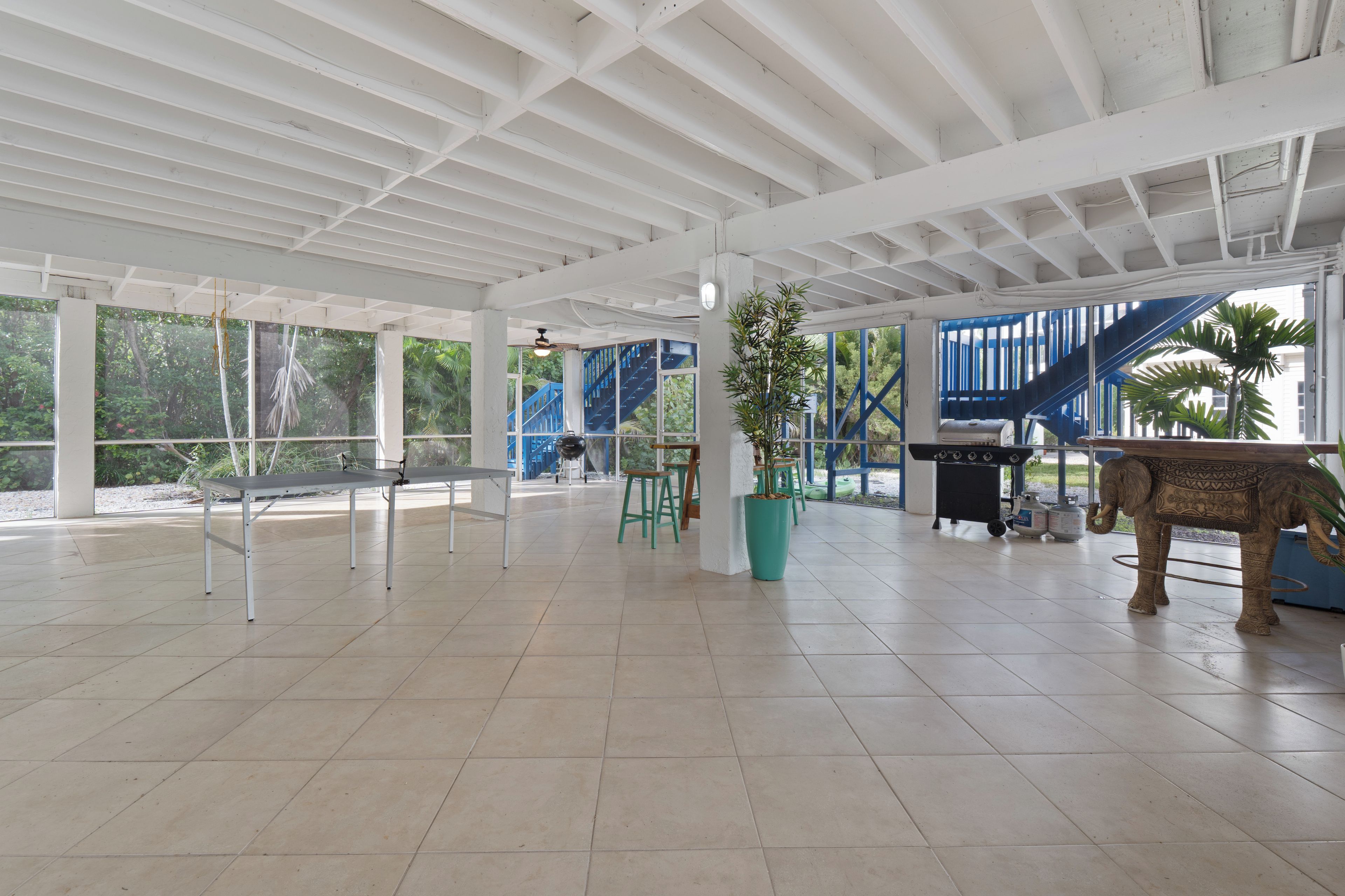 Un'ampia area interna con soffitto alto, ampie finestre e vista su una scala blu.
