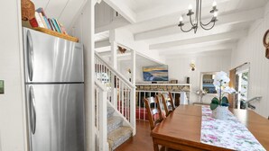 A spacious kitchen with a large stainless steel refrigerator, wooden dining table, and a staircase leading to an upper level. - Walk to the lake Gorgeous lake house (Big Bear Lake)