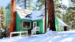A green cabin with a white porch, surrounded by snow and trees. - Walk to the lake Gorgeous lake house (Big Bear Lake)