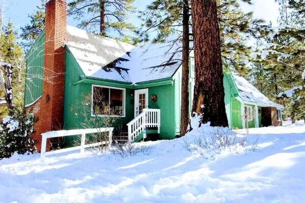 A green cabin with a white porch, surrounded by snow and trees. - Walk to the lake Gorgeous lake house (Big Bear Lake)
