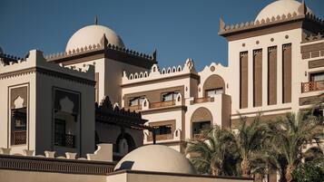 A multi-story building with domed structures, balconies, and palm trees.