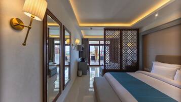 A hotel room with a large bed, a sitting area, a view through a glass door, and a decorative partition.