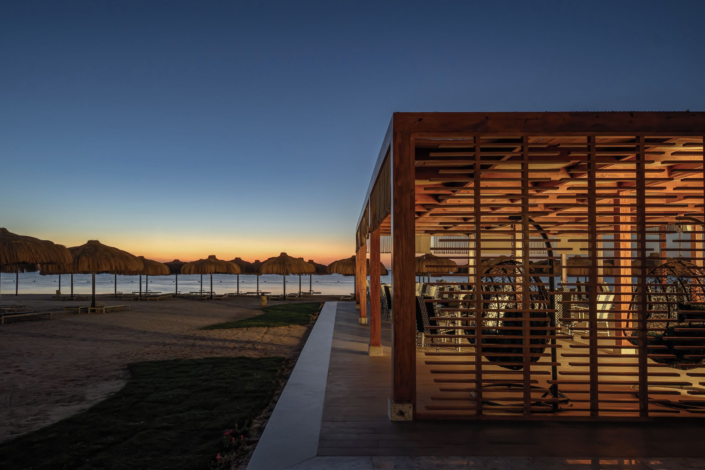A modern building with a wooden exterior and a view of the beach and mountains in the background.