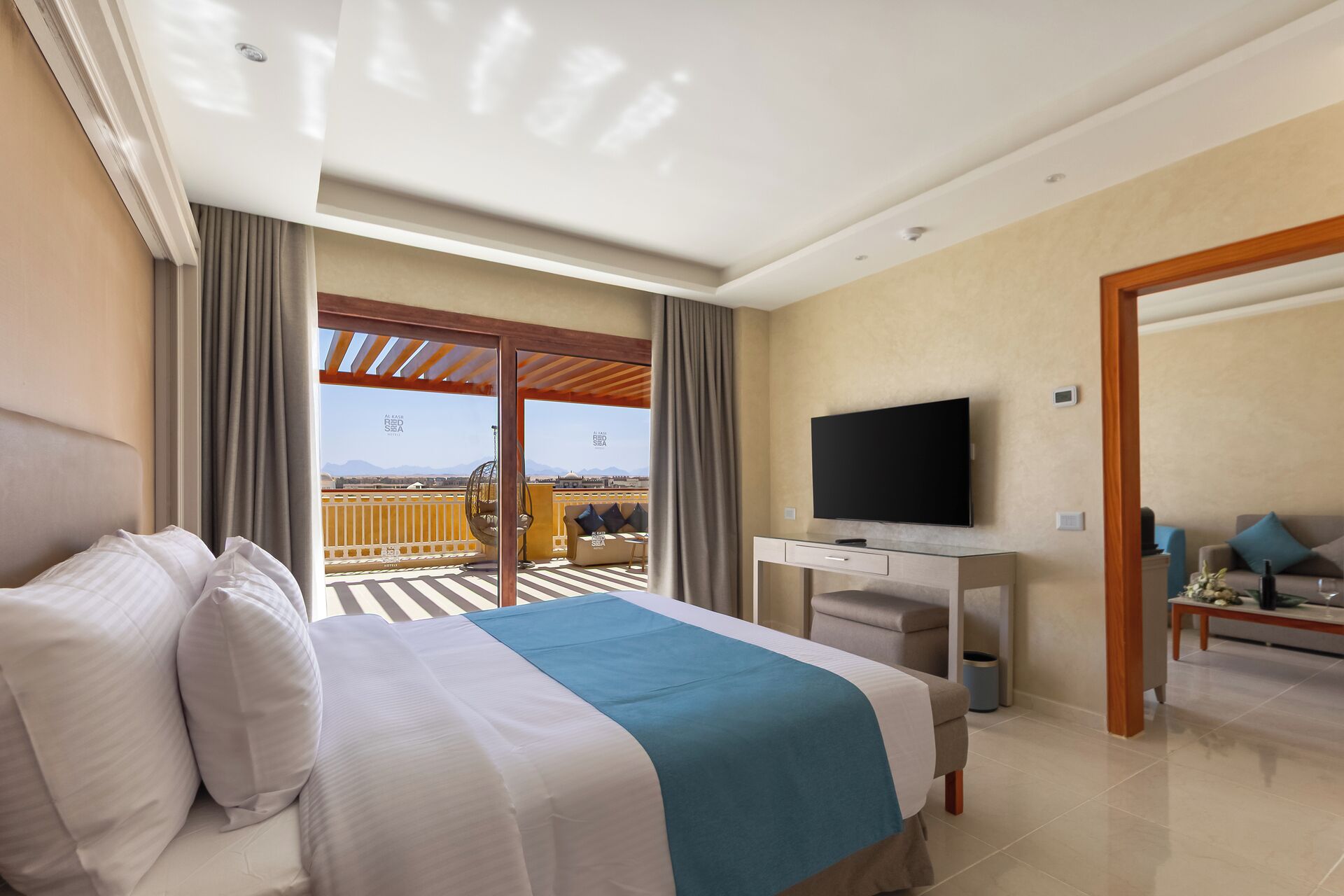 A hotel room with a bed, a TV, a desk, and a balcony with a view.
