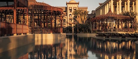 A pool with reflections, a pavilion, and a building with columns.