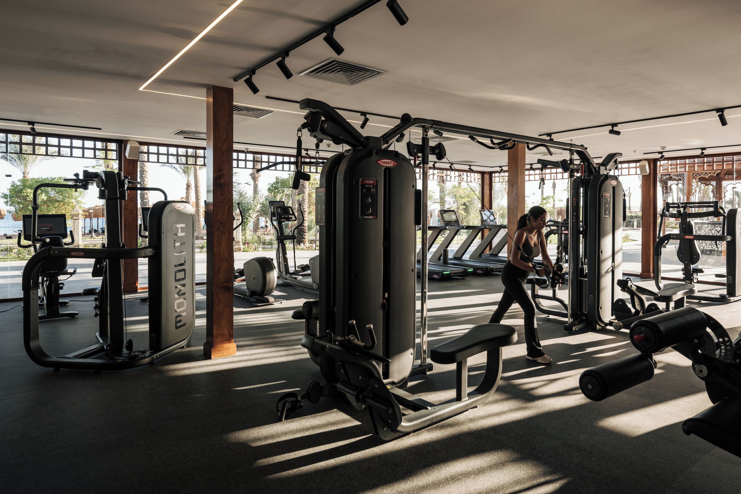 Un gimnasio con equipo de ejercicio, una banca y una persona entrenando.
