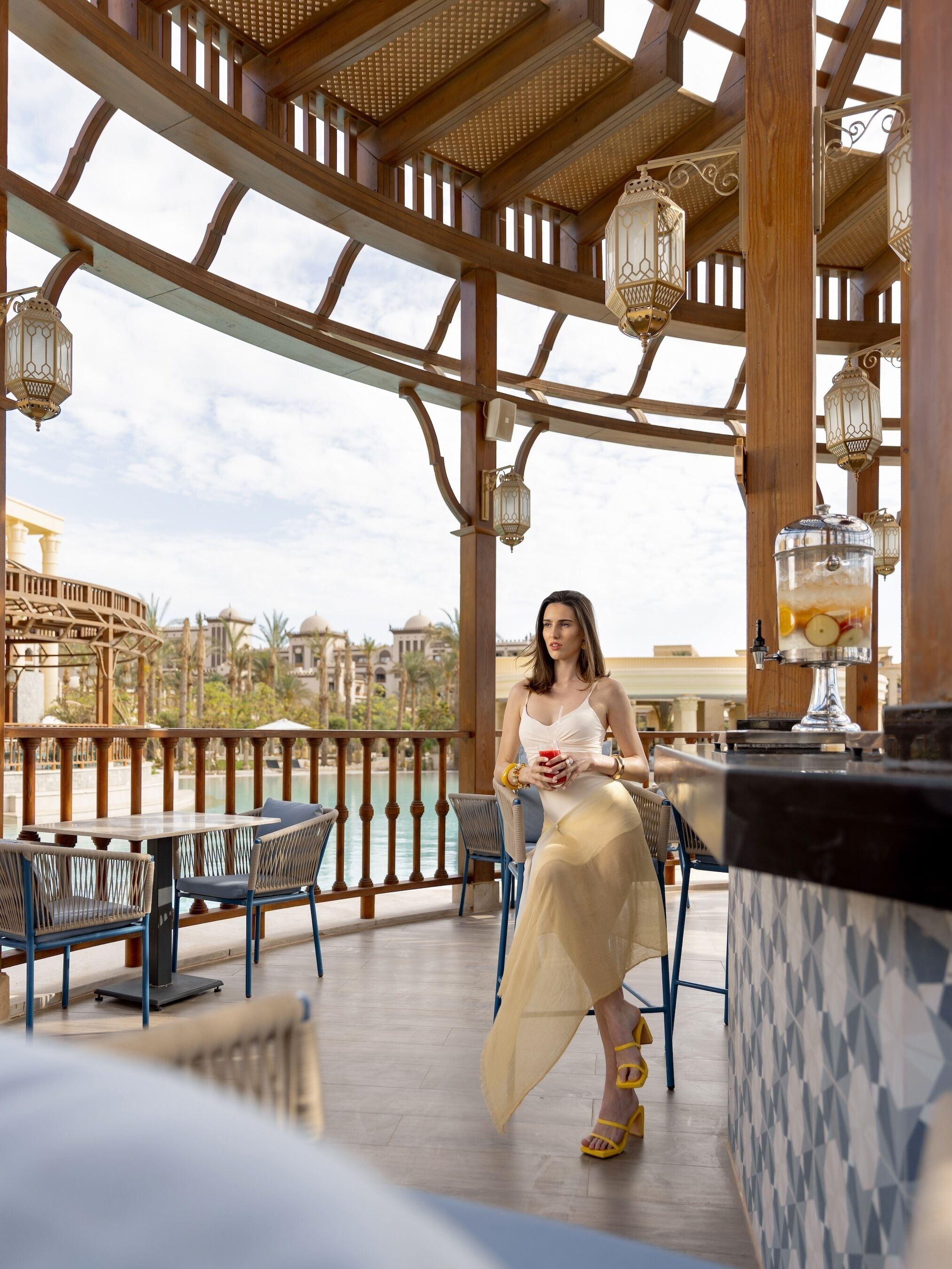 A covered outdoor seating area with a view of a body of water and buildings in the background.