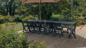 An outdoor patio with a table and chairs, surrounded by greenery and trees. - Quiet house in a large park. Close to the coast and shops! (Lamballe-Armor)