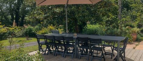 An outdoor patio with a table and chairs, surrounded by greenery and trees.