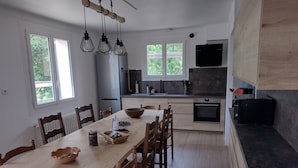 A modern kitchen with a wooden dining table, chairs, and pendant lights. - Quiet house in a large park. Close to the coast and shops! (Lamballe-Armor)