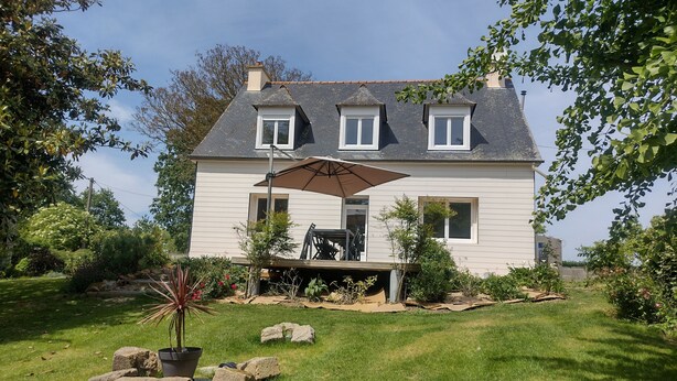 A two-story house with a covered patio, a lawn, and surrounding greenery. - Quiet house in a large park. Close to the coast and shops! (Lamballe-Armor)