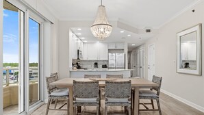 A modern kitchen with white cabinets, a central island, and a chandelier. - Enclave 607 (Orange Beach)