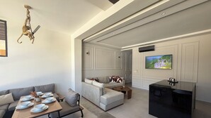 Una sala de estar moderna con un sofá, una mesa de comedor y un televisor montado en la pared.