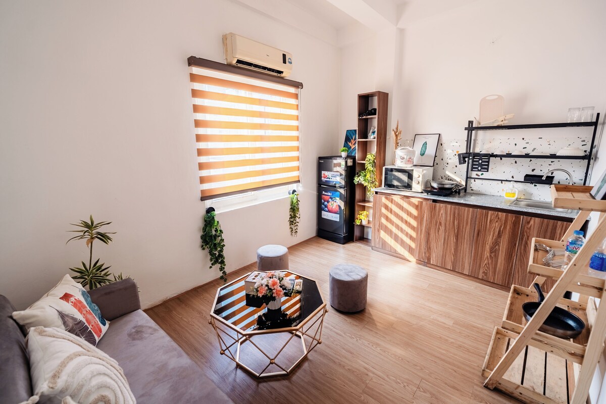A compact living space with a kitchenette, a dining area with a hexagonal table, and a seating area with a sofa.