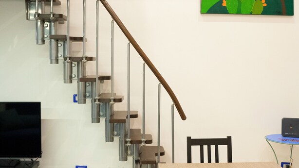 Ein modernes Wohnzimmer mit Treppe, Essbereich und einem farbenfrohen Gemälde an der Wand.