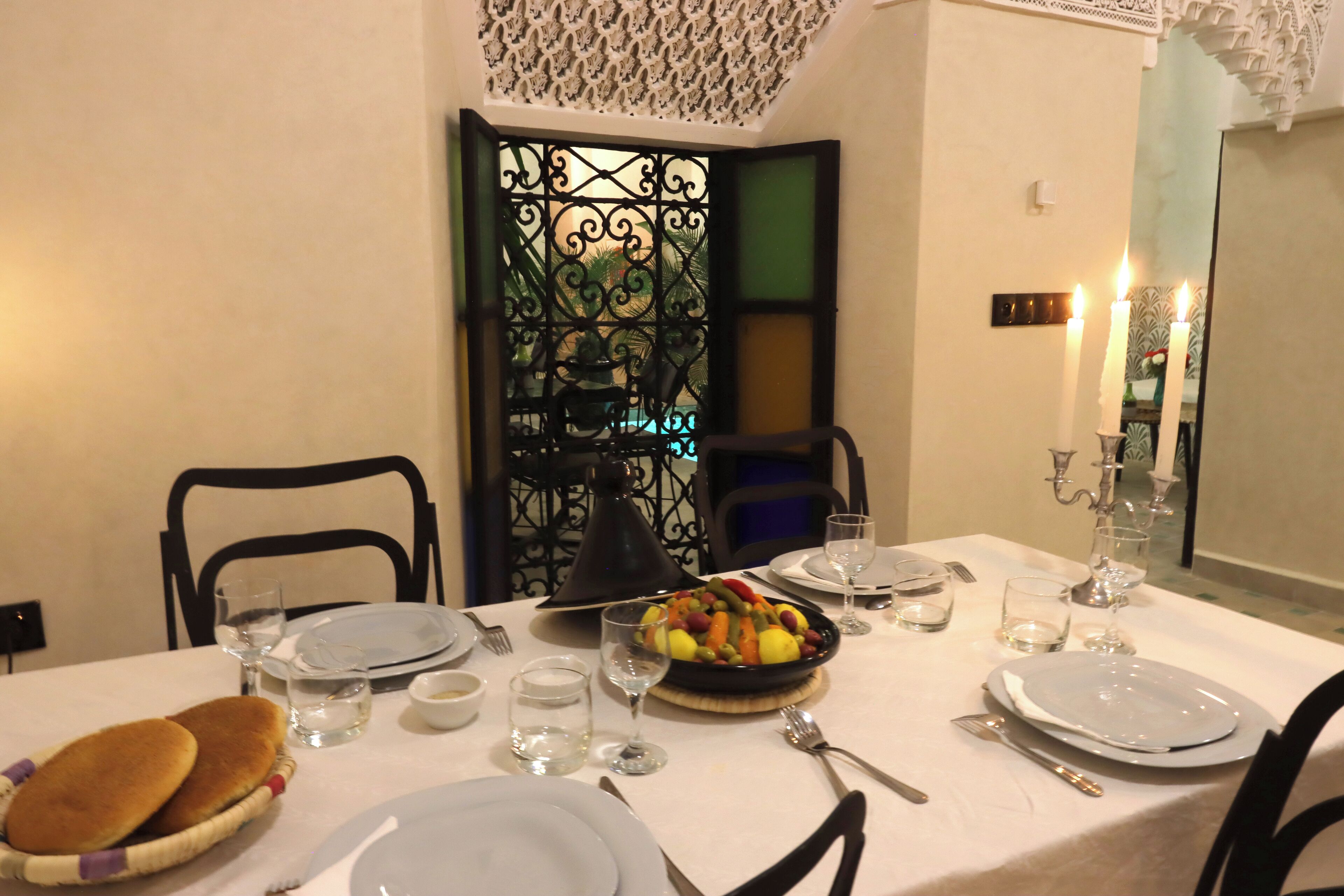 A dining table set with plates, cutlery, glasses, and a fruit bowl.