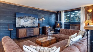 A cozy living room with a large flat-screen TV, a fireplace, and a comfortable sofa set. - Luxury Catered Ski Chalet Iona in Meribel, France LMRB-9 (Meribel)