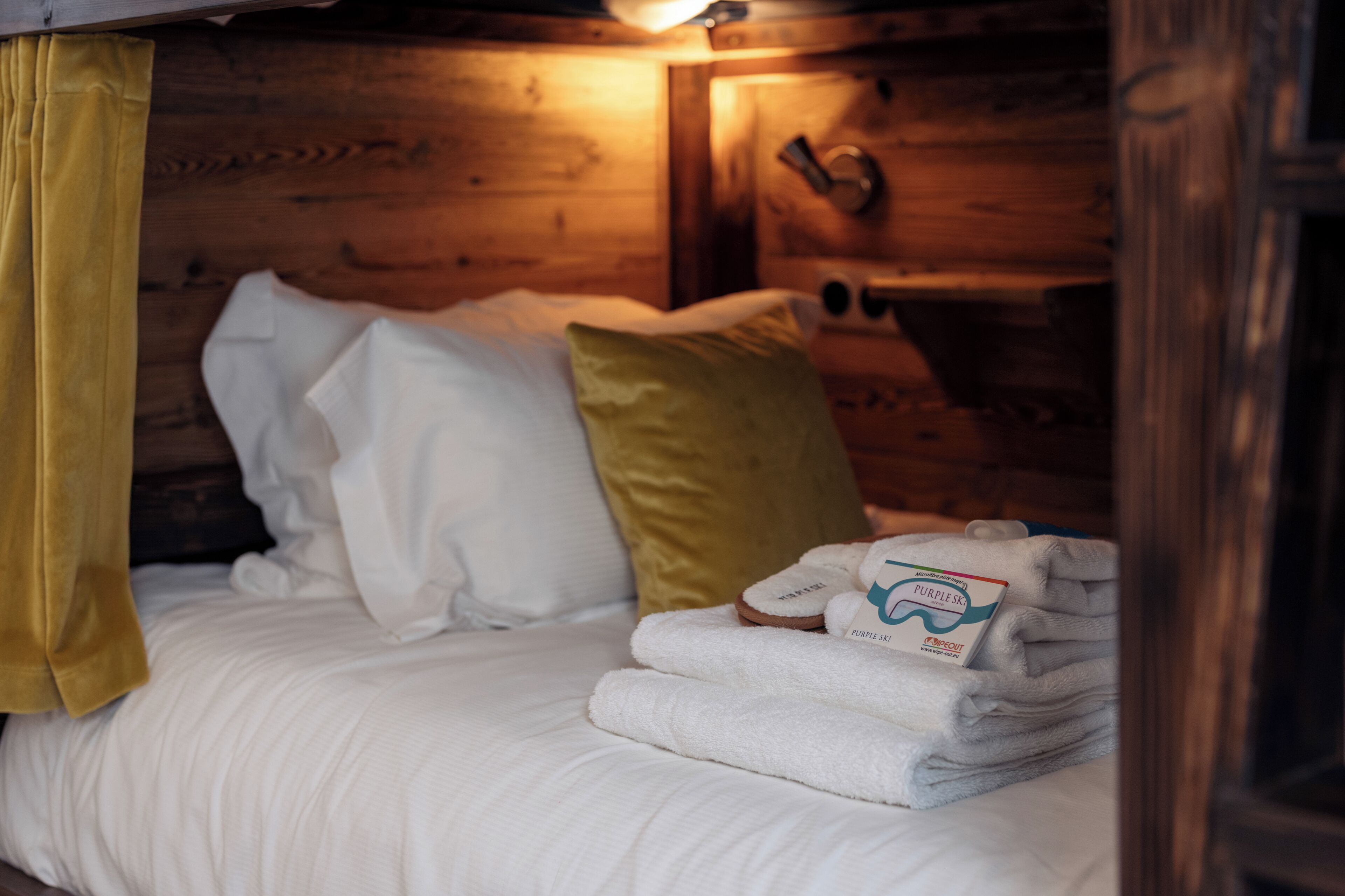 Une chambre dans un chalet en bois, avec un lit, des oreillers et une pile de serviettes.