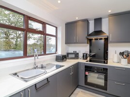 A modern kitchen with grey cabinets, a built-in oven, a microwave, and a sink.