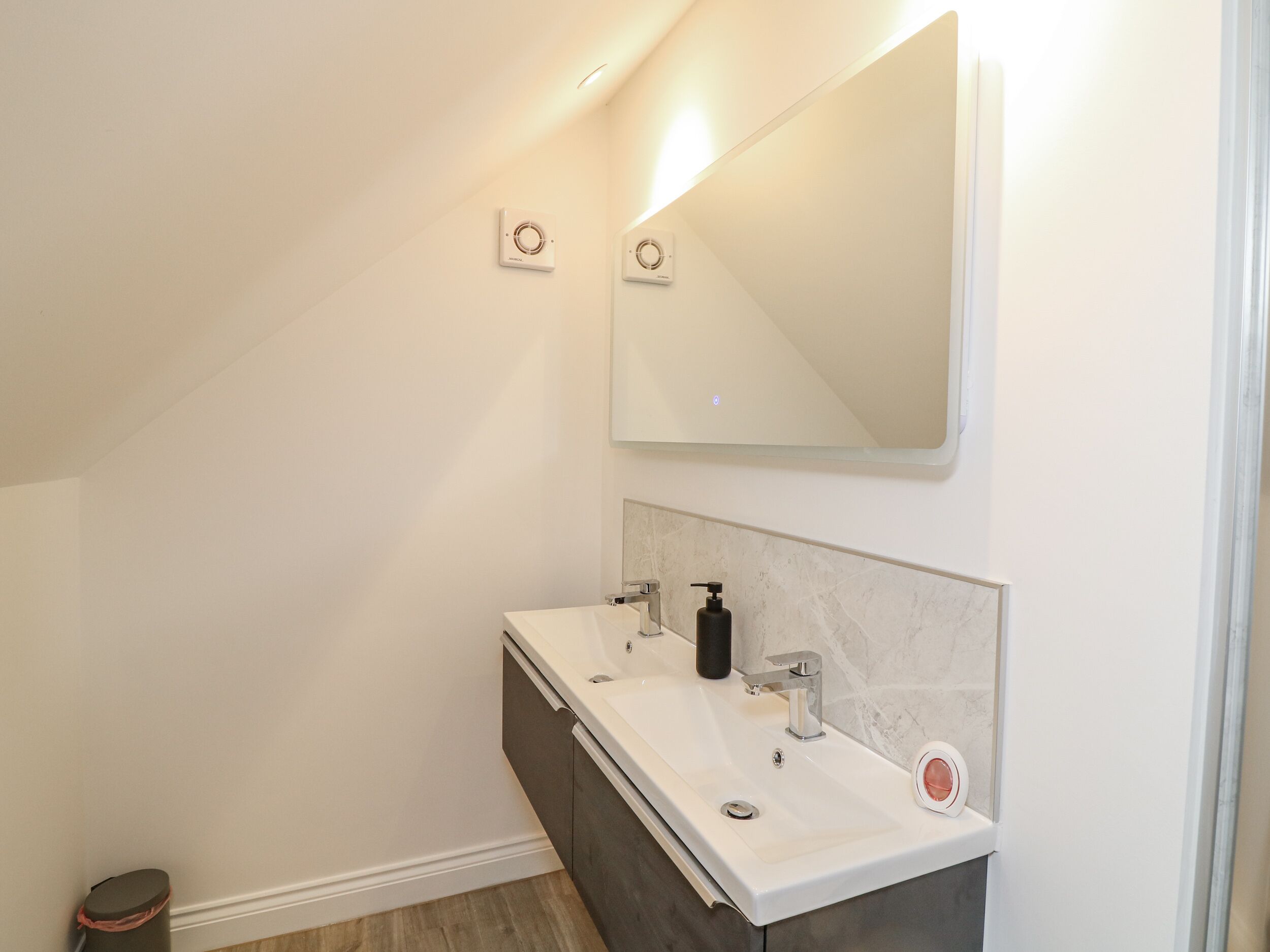 Une salle de bain moderne avec un meuble-lavabo blanc, un grand miroir et des toilettes.