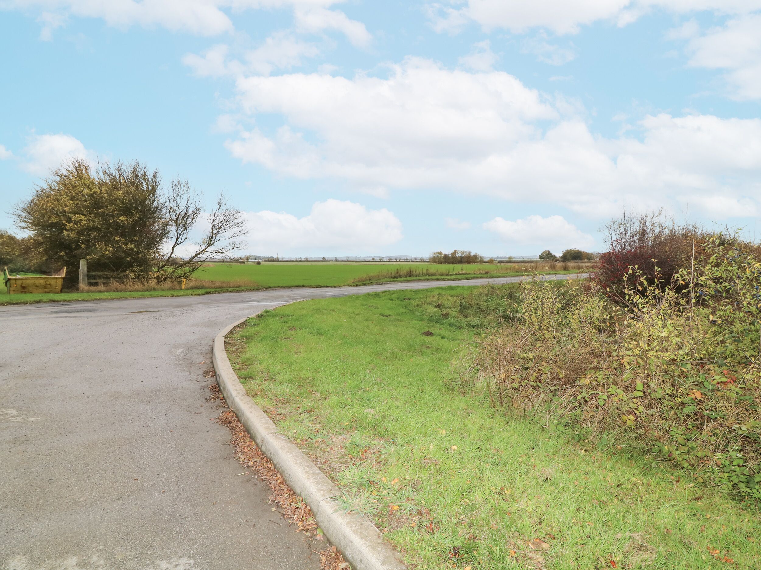 Eine kurvenreiche Landstraße durch eine grüne Landschaft mit Feldern und Bäumen.