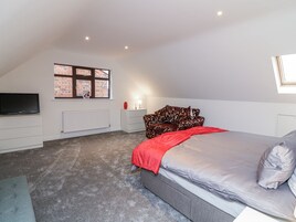 A bedroom with a bed, a TV, a radiator, and a window with a brick wall view.